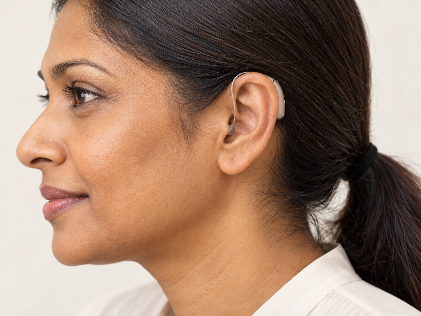 Receiver-in-Canal (RIC) discreet hearing aid fitted on a woman's left ear