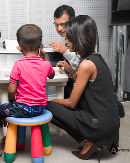 Child with mother and audiologist conducting post-implant hearing evaluation at Wickramarachchi Hearing Care