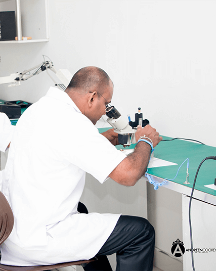 Senior technician inspecting hearing aid micro-components under microscope at Wickramarachchi Hearing Aid Repair Lab